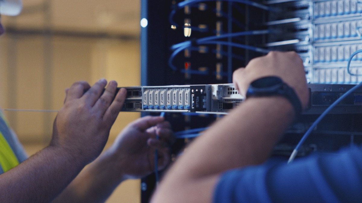 Two engineers fitting a server into a rack in a data hall