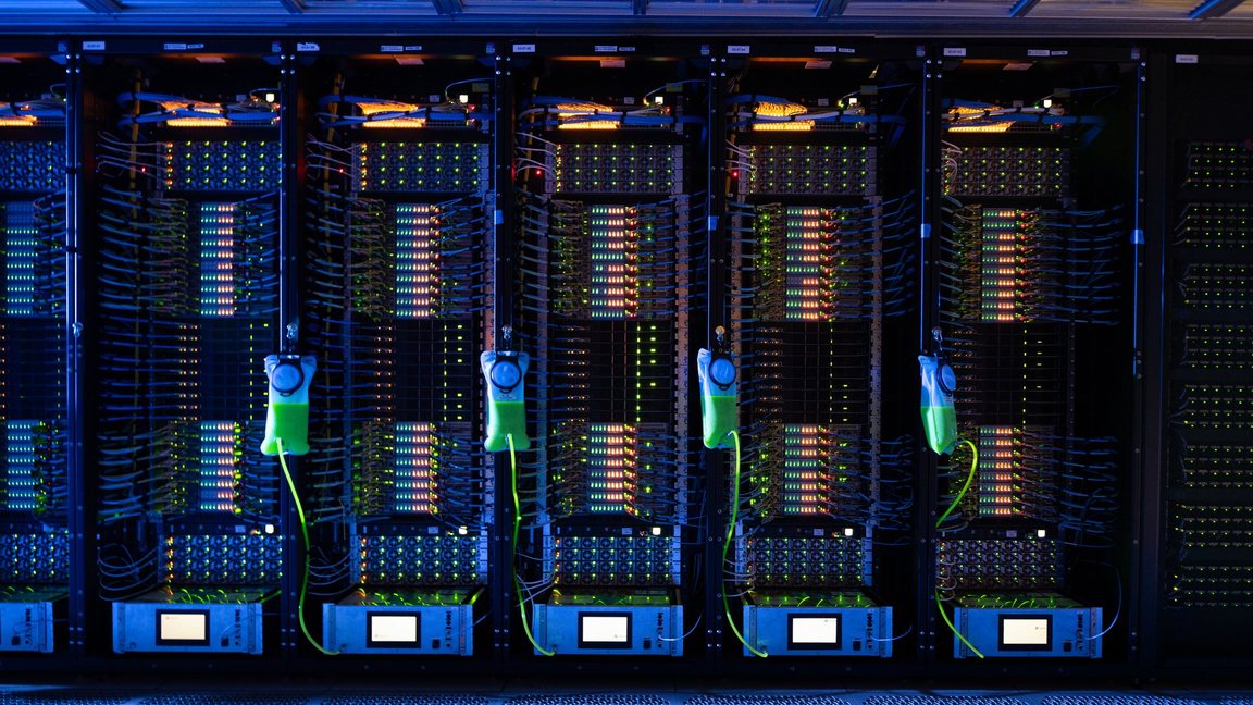 A row of server racks in a data hall, cables lit green